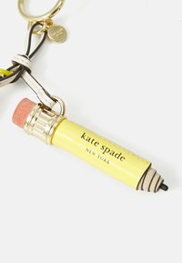 Yellow Kate Spade New York keychain shaped like a pencil with a pink eraser and black tip on a white background.