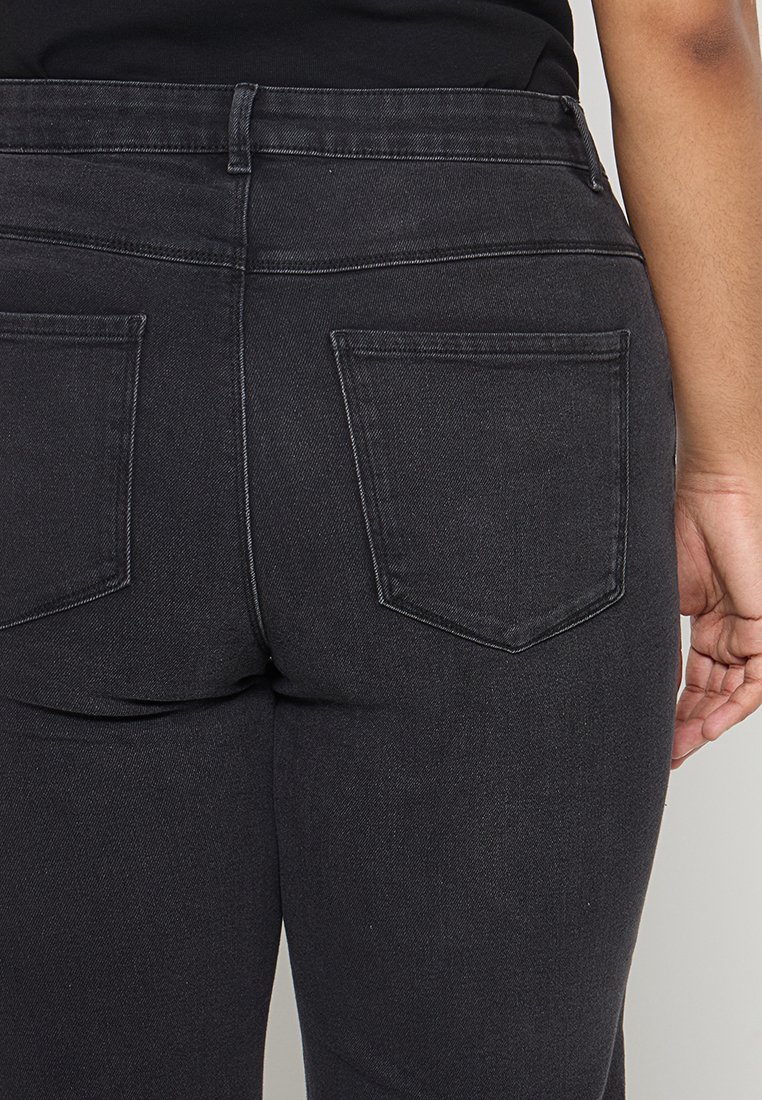 Schwarze Denim-Jeans mit einer taillierten Passform, hoher Taille und zwei Gesäßtaschen mit auffälliger Naht. Glatte Textur und schmaler Beinabschluss.