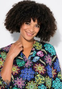 Farbige Bluse mit Blumen- und Totenkopf-Mustern auf schwarzem Hintergrund. Kurze Ärmel und ein V-Ausschnitt-Design, gefertigt aus einem glatten Stoff.