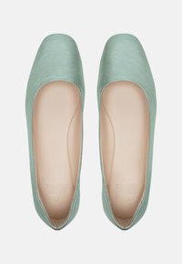 Ballerines en satin vert menthe avec un bout rond, un éclat subtil et un intérieur lisse. Présentent un fin bord contrastant tout autour.