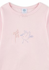 Light pink top featuring a round neckline, a bow accent, and a blue bird graphic next to a simple flower design. Smooth fabric texture.