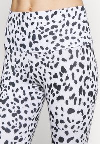 High-waisted leggings in a stretch fabric, featuring a black and white speckled pattern with a smooth texture and fitted design.