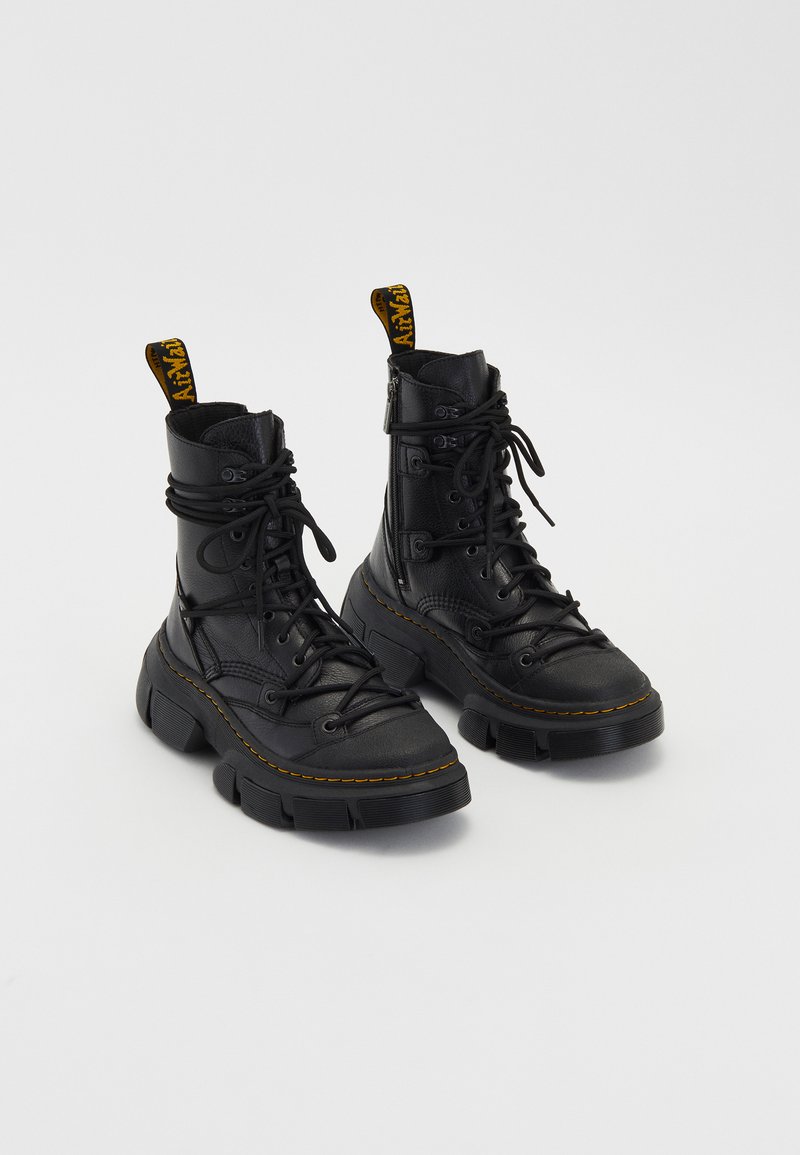 Black leather combat boots with a textured finish, chunky rubber sole, yellow stitching, and a pull tab on the heel. Laced design.