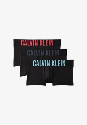 Drie paar zwarte herenshortboxers op elkaar gestapeld, elk met een "Calvin Klein" logo in een andere kleur op de tailleband: rood, donkerblauw en lichtblauw.
