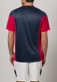 Lyhythihainen urheilupaita, jossa on tummansininen vartalo ja vaaleanpunaiset hihat. Sujuva, kevyt kangas, jossa on kontrastivärisiä paneeleja.