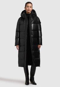 Schwarze Pufferjacke mit Kapuze, glänzender Oberfläche, gestepptem Design, langen Ärmeln und geradem Schnitt, der bis zur Mitte der Waden reicht.