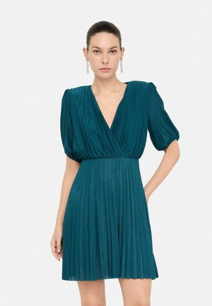 Abito plissettato color teal con scollatura a V, maniche corte a sbuffo e tessuto scintillante. Presenta una vita aderente e una gonna a campana.
