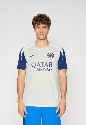 T-shirt de sport gris clair avec des manches bleu foncé. Présente le logo Nike et "Qatar Airways" en lettres marine. Fabriqué en matériau respirant.