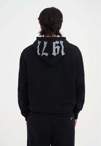 Sudadera negra de algodón, con capucha y gran letras plateadas "IL 61" en la parte posterior. Textura suave y corte relajado.