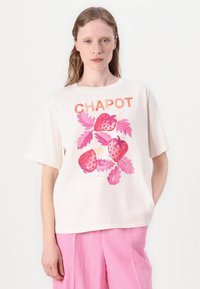 Witte katoenen t-shirt met een kleurrijke aardbei en blad grafiek, met het woord "CHAPOT" in oranje bovenaan. Korte mouwen, ontspannen pasvorm.