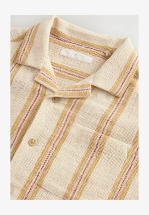 Chemise beige avec un tissage texturé, dotée d'accents rayés jaunes et rouges. Comprend un col et une poche poitrine avec fermeture à bouton.