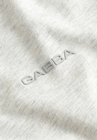 Tessuto grigio chiaro con logo GABBA ricamato a rilievo in filo grigio abbinato vicino al centro.