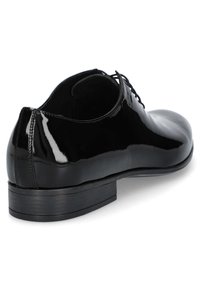 Czarne lakierowane oxfordy o smukłym designie, zaokrąglonym nosku i niskim, warstwowym obcasie. Posiadają sznurowane zapięcie z przodu i gładką powierzchnię.