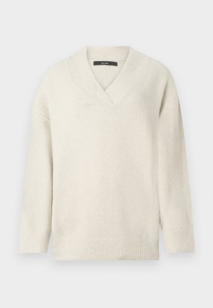 V-hals sweater i lys creme, lavet af blødt materiale. Har sænkede skuldre, ribbet ærmekanter og en afslappet pasform.