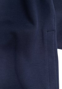 Tessuto in cotone morbido di colore blu navy con una superficie liscia. Presenta una cucitura a sinistra e un design semplice e minimalista senza decorazioni.