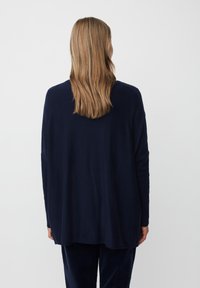 Granatowy longsleeve z luźnym krojem, zaokrąglonym dołem i miękką fakturą. Posiada szeroki dekolt i opadające szwy ramion.