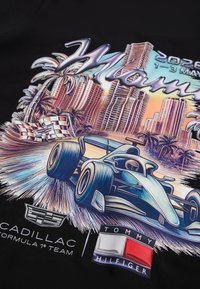 Αυτοκίνητο της Formula 1 που τρέχει με φοίνικες και ορίζοντα πόλης, λογότυπα Cadillac και Tommy Hilfiger, κείμενο Miami Grand Prix Μάιος 2026.