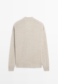 Beżowy sweter z dzianiny o miękkiej, teksturowanej powierzchni. Posiada prążkowany dół i mankiety oraz subtelny, lekki design, który doskonale nadaje się do noszenia warstwowego.