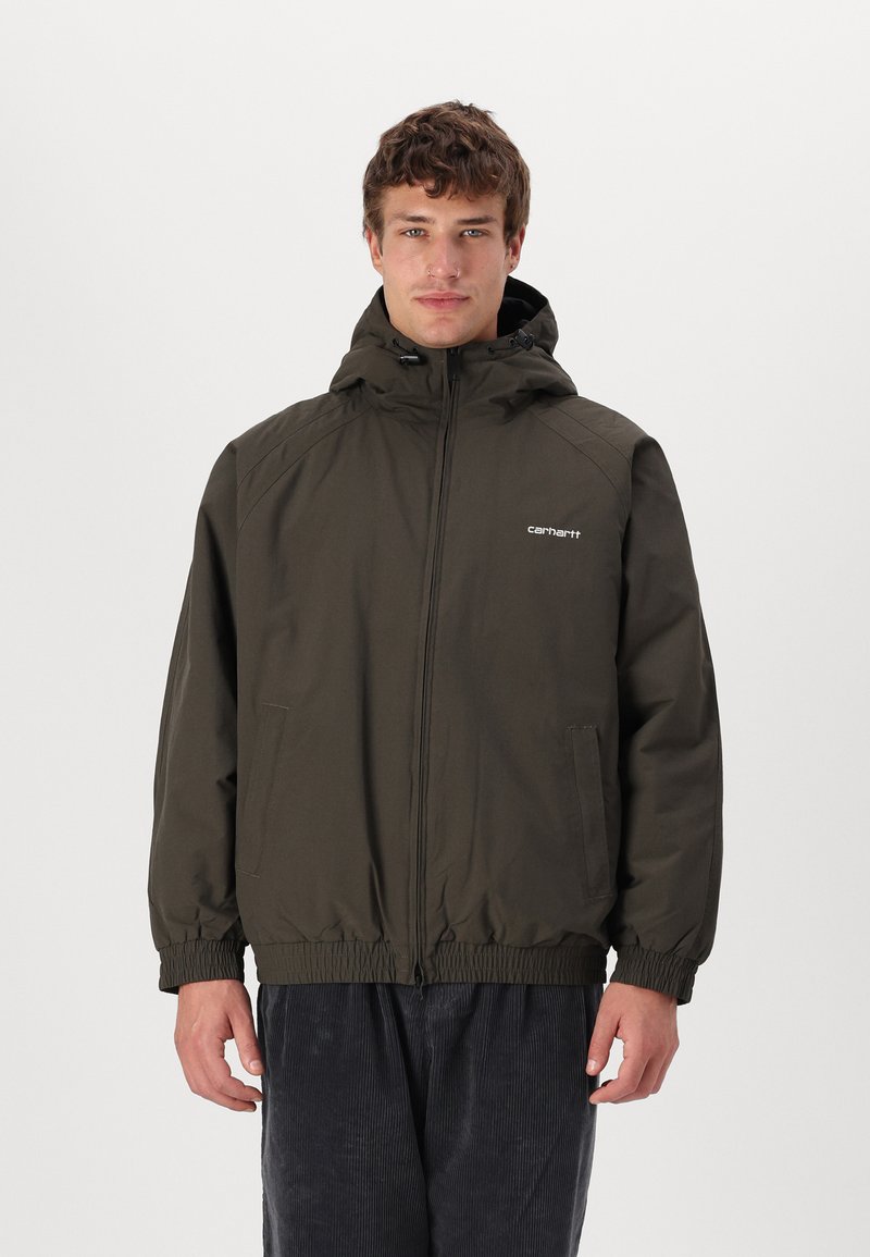 Veste à capuche vert olive avec fermeture éclair à l'avant, poignets élastiques et ourlet. Présente un logo sur la poitrine et deux poches latérales. Tissu texturé.