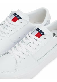 Białe skórzane sneakersy z okrągłym noskiem, płaskimi sznurówkami, małymi perforacjami oraz granatowym i czerwonym akcentem na języku. Gumowa podeszwa.