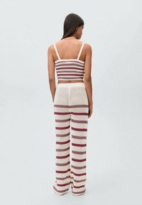Set coordinato in crochet con top fitted senza maniche a righe rosse e crema e pantaloni a gamba larga con un motivo a righe simile.