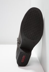 Czarny botek na kostkę z teksturowaną gumową podeszwą, z bocznym zamkiem błyskawicznym i górą ze gładkiej skóry. Ozdobiony logo na podeszwie.