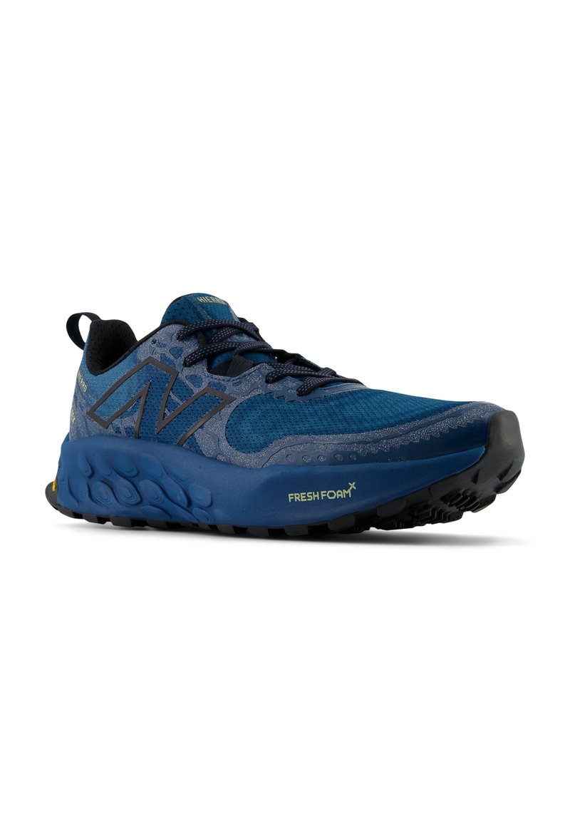 Blaues Sport-Schuhwerk mit einem Obermaterial aus Mesh, Gummilaufsohle, gepolstertem Schaft und strukturiertem Zwischensohlenelement mit gelben Akzenten. Die Schnürsenkel sind dunkelblau.