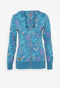 Sudadera azul con cremallera y un patrón floral en morado claro y verde azulado. Cuenta con capucha, cordones y un pequeño parche de logo en el frente.