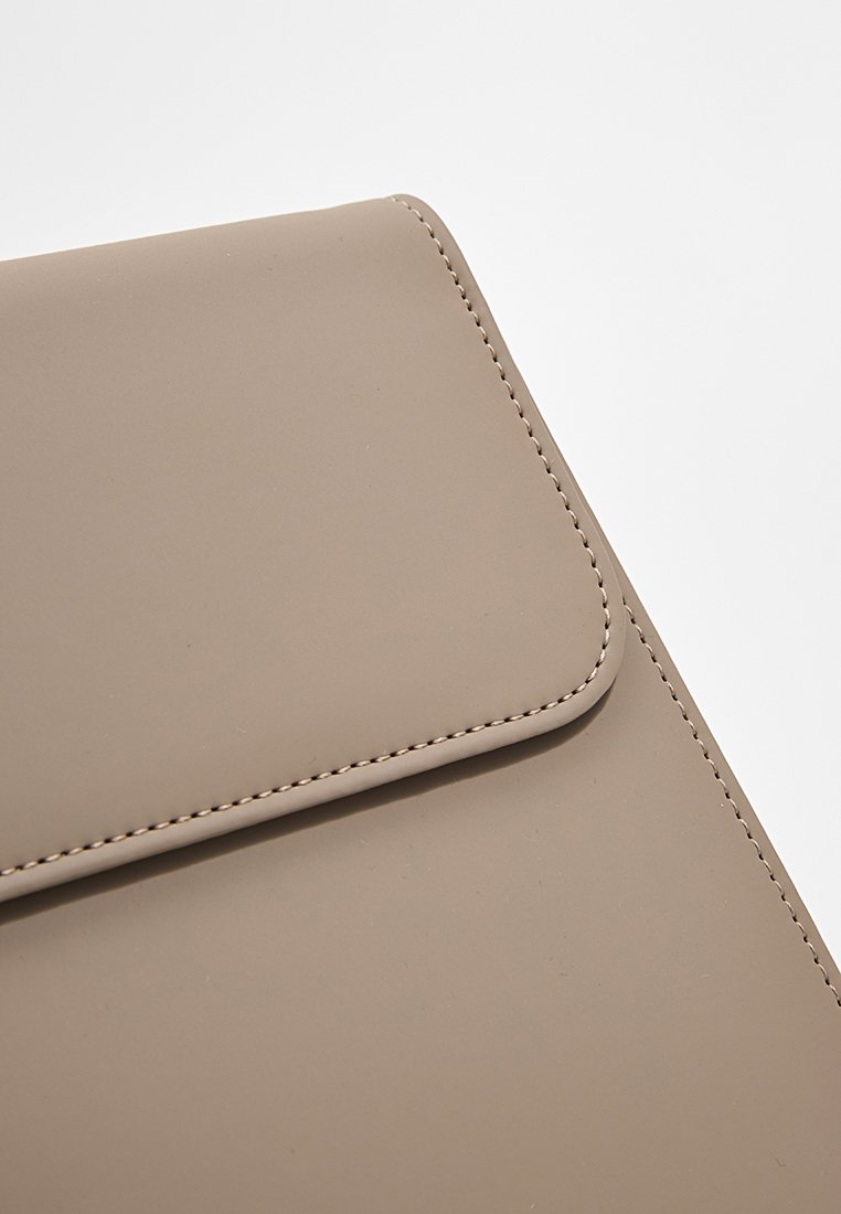 Pouch in materiale sintetico beige con una superficie liscia, angoli arrotondati e cuciture a contrasto lungo i bordi, dotato di chiusura a pattina.