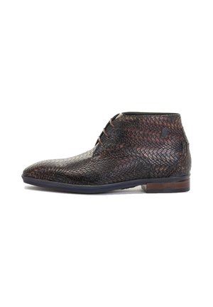 Bottine chukka en cuir brun avec une texture tissée, bout pointu et lacets bruns. Présente un talon bas et une semelle foncée contrastante.