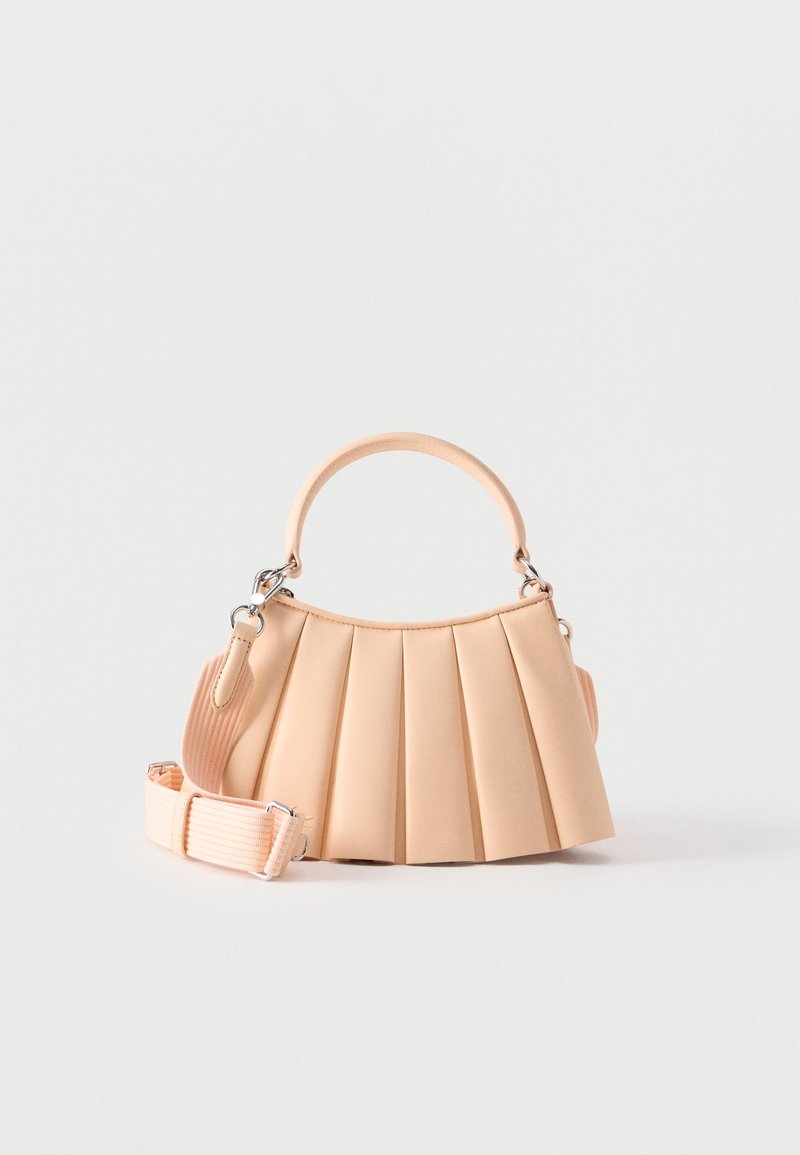 Sac à main plissé beige avec poignée arrondie et bandoulière en tissu côtelé détachable sur fond blanc.