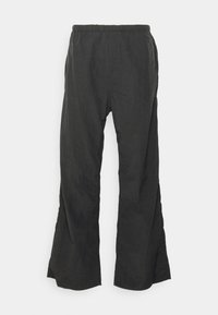 Pantalons noirs à coupe ample, en tissu léger, dotés d'une taille élastique et d'ouvertures de jambes évasées avec une surface texturée.
