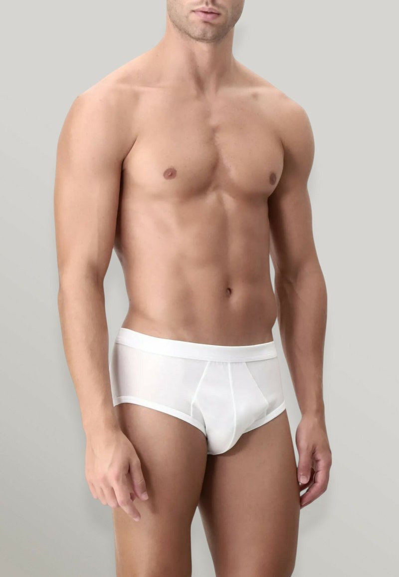 Slip in cotone bianco con una consistenza liscia, dotato di una vita solida e una tasca frontale, progettato per comfort e supporto. Corpo mostrato di lato.