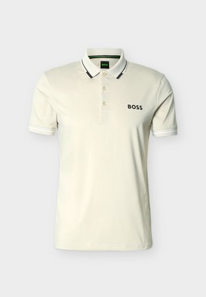 Kremowa koszulka polo z krótkim rękawem i trzema guzikami, kołnierzyk z czarną lamówką oraz logo „BOSS” na lewej piersi.