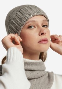 Szara dzianinowa czapka typu beanie z fakturowanym prążkowaniem i srebrnymi koralikami, w zestawieniu z gładkim, jasnoszarym szalikiem. Miękki materiał z włóczki, zapewniający przytulne dopasowanie.