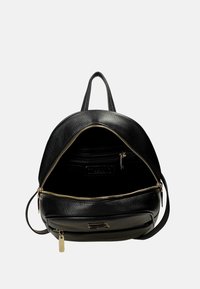 Zaino in pelle nera con design arrotondato, dettagli in zip dorata e tasca interna. Superficie testurizzata con doppie cinghie e manico superiore.