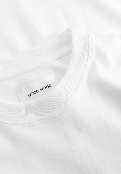 White cotton t-shirt with a ribbed crew neckline. Features a woven label with "WOOD WOOD" in black text. Smooth texture, no visible patterns.