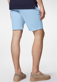Jasnoniebieskie bawełniane szorty o prostym kroju, wyposażone w boczne kieszenie. Połączone z beżowymi butami typu slip-on o teksturowanym wykończeniu.