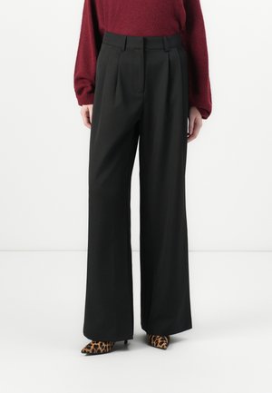 Black wide-leg trousers with pleated front, high waist, and a smooth texture, paired with pointed leopard print heels.