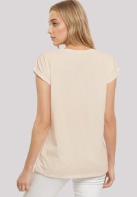 Light beige short-sleeve t-shirt with rolled sleeves, rounded neckline, soft texture, and a relaxed fit. No visible patterns or accents.