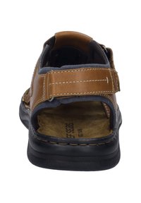 Brown leather sandal featuring a dark grey fabric lining, adjustable strap, and a cushioned footbed with a textured sole.
