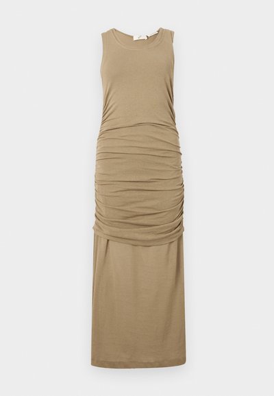 Rochie maxi fără mâneci dintr-un material moale, texturat, de culoare bej. Are detalii plisate pe lateral, creând o siluetă drapată.