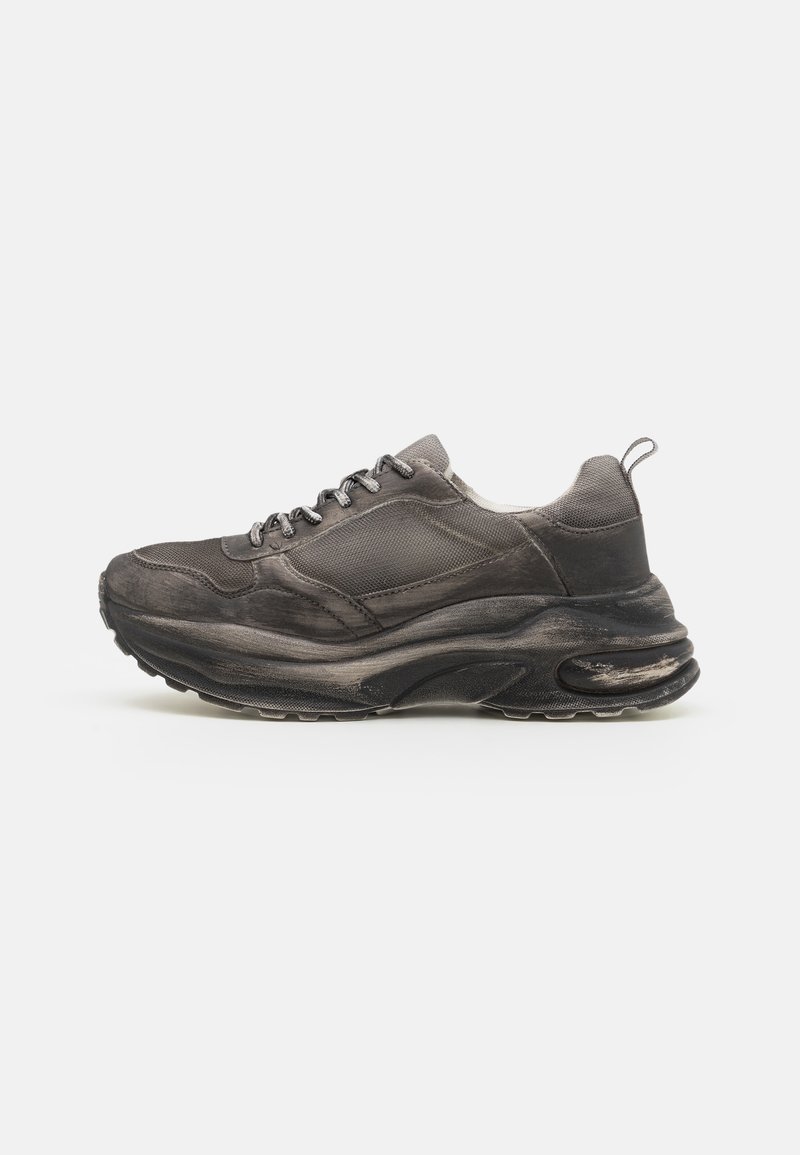 Black athletic shoe with textured fabric upper, padded collar, and a thick midsole, featuring a rubber outsole and lace-up closure.