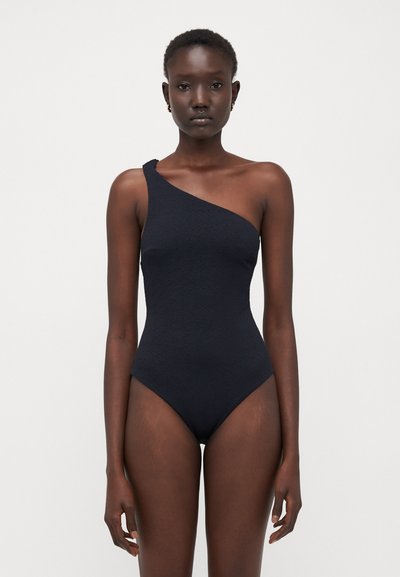 Costume da bagno nero monospalla realizzato in tessuto testurizzato. Presenta un design elegante e aderente con una gamba alta e uno stile minimalista.