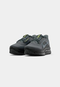 Tmavé šedé bežecké topánky Nike Air Max s čiernymi podrážkami a reflexným swooshom, šikmý predný pohľad na bielom pozadí.