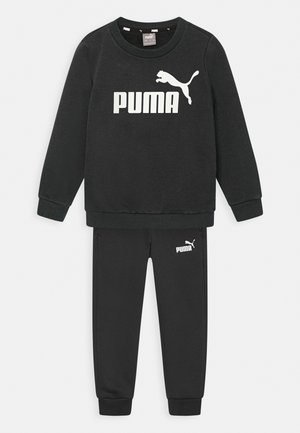 Conjunto de sudadera y pantalones negros de tela suave. Presenta un logo y marca en blanco. Puños y escote acanalados para mayor textura.