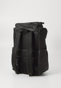 Black backpack with a roll-top closure, made of textured fabric. Features padded shoulder straps and mesh side pockets for storage.