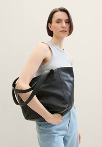 Ampia borsa a tote nera in pelle testurizzata, con pannelli lisci e pattern. Doppi manici, design morbido e interno spazioso.
