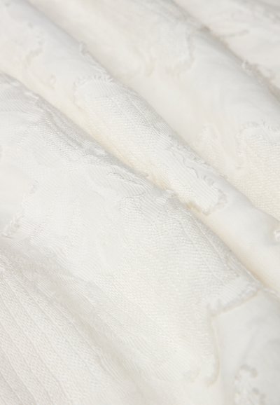 Tessuto bianco testurizzato, con un motivo sottile caratterizzato da aree in rilievo, finitura liscia e dettagli intrecciati intricati in tutto il tessuto.