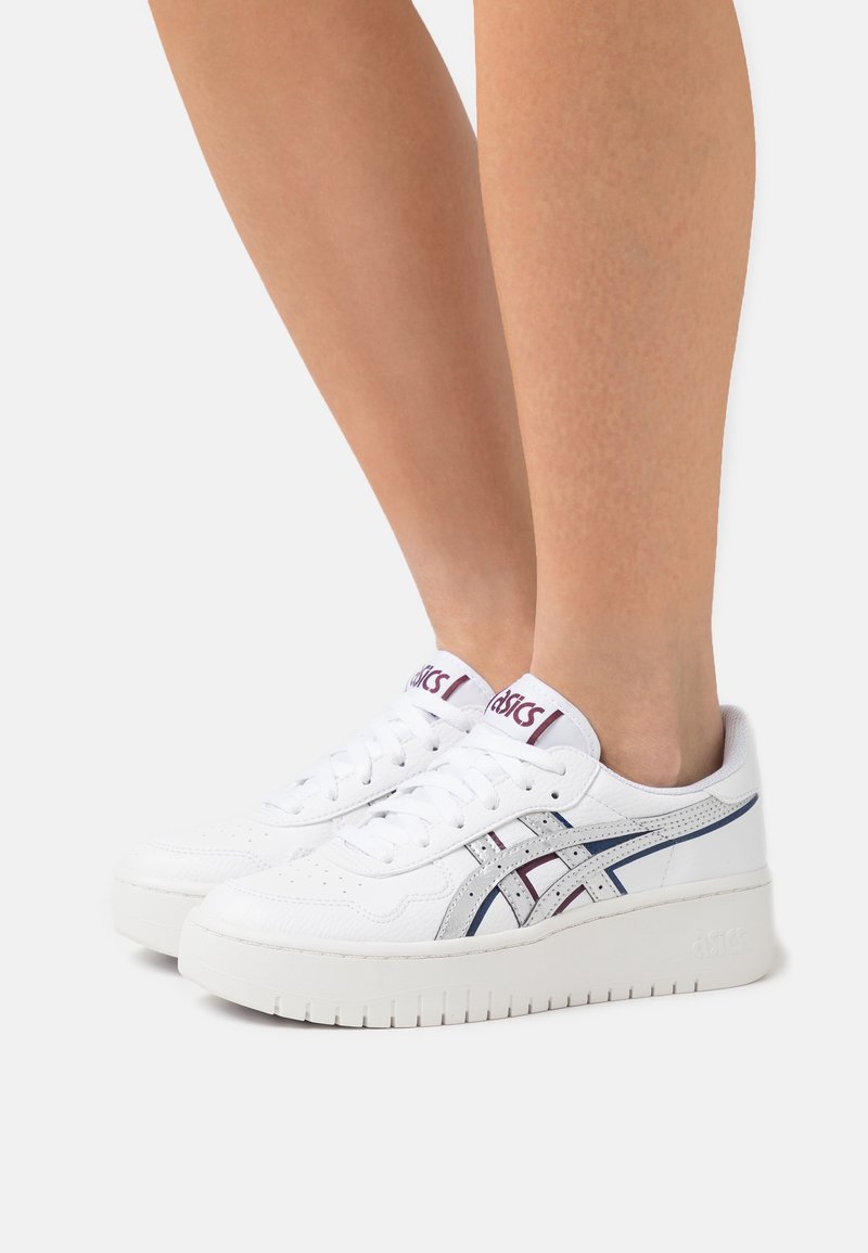 Bílé kožené tenisky s tlustou bílou podrážkou, se stříbrnými a vínovými akcenty, kulatou špičkou a šněrováním v přední části.